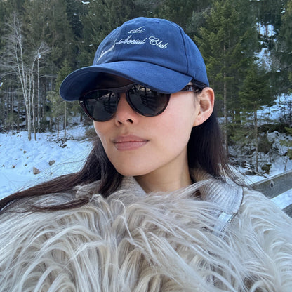Model wearing Ciren oval tortoiseshell sunglasses and wearing Greenwich Social Club logo baseball cap